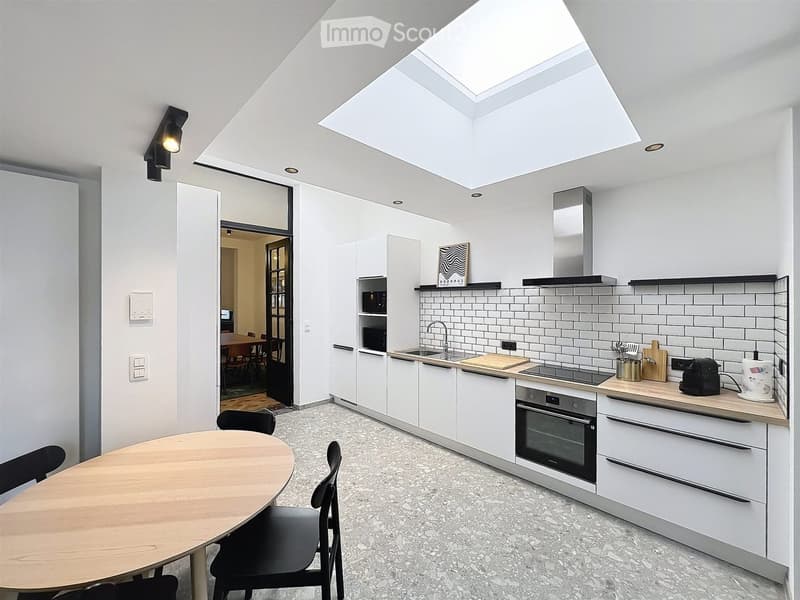 Modern kitchen with white cabinets, stainless steel appliances, and a skylight. Includes a dining area with a round table and chairs.