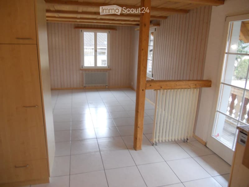 Empty room with white tiled floor, wooden beams, and large windows. No furniture or equipment present.