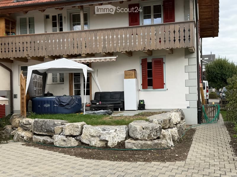 Garden area with a hot tub, sofa, table, tent, and refrigerator near the house.