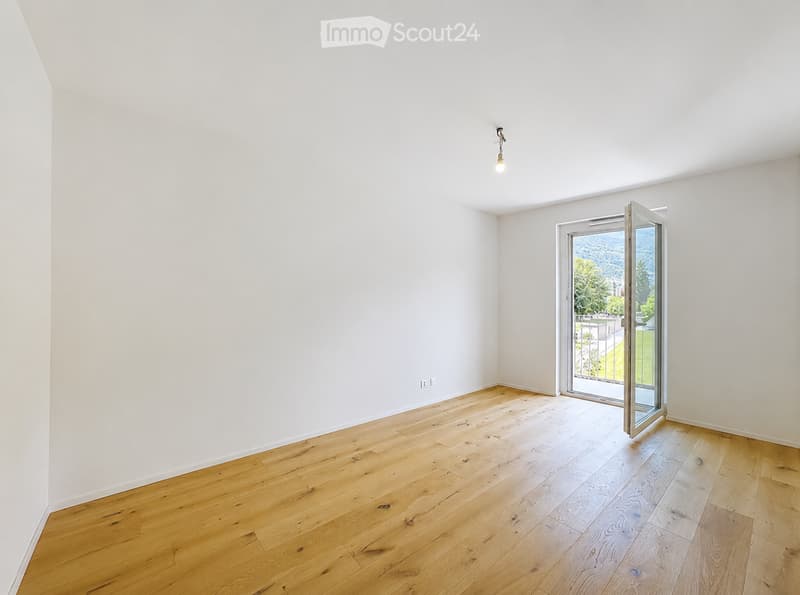 Empty room with light wooden flooring, white walls, and a large open sliding door leading to a balcony or outdoor area.