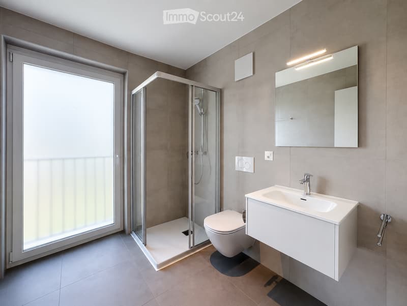 Modern bathroom with a white sink, mirror, toilet, and glass-enclosed shower stall. Features include a sleek design with beige tiles and a built-in storage cabinet.