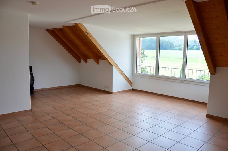 Empty room with tiled floor, white walls, large window with view, wooden staircase leading upwards.