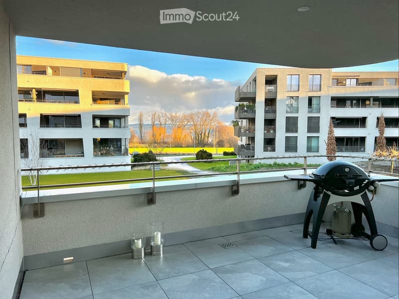 Balcony with tiled floor, metal railing, grill, and candles on the floor.