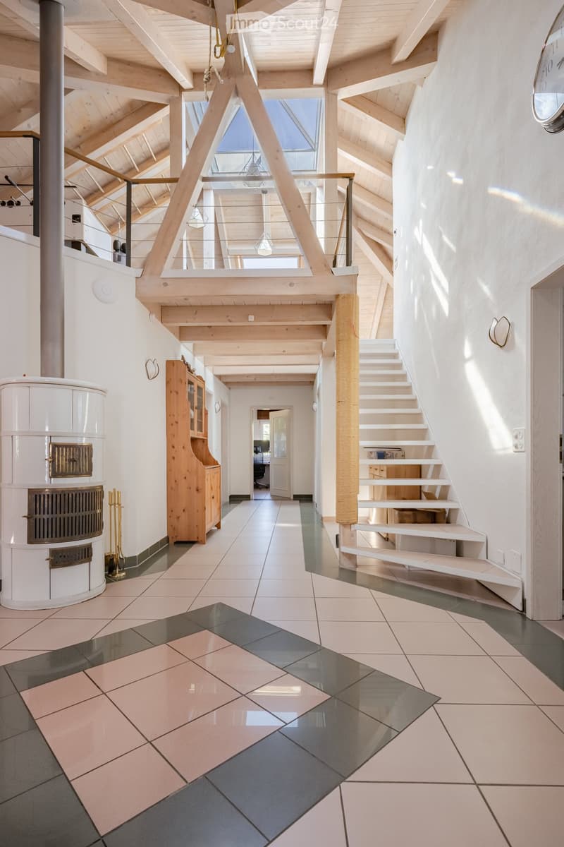 Modern hallway with wooden beams, white walls, tiled floor, staircase leading to an upper level, and a built-in wooden cabinet.