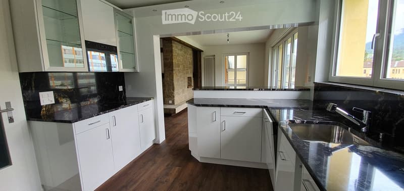 Modern kitchen with white cabinets, black countertops, and a stainless steel sink.