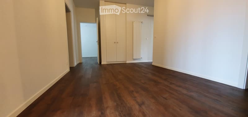 Empty room with wooden flooring, white walls, and a built-in wardrobe. No furniture or equipment present.