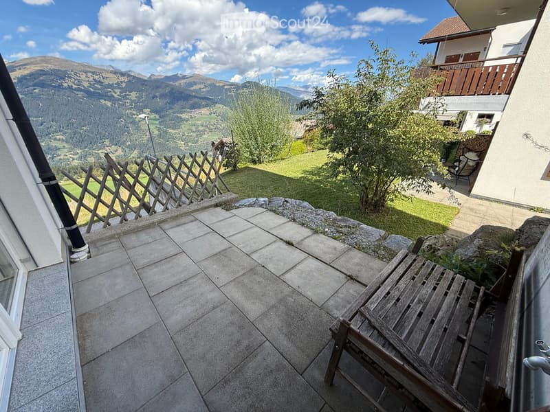 Balcony with tiled floor, wooden chair, wooden fence, and scenic mountain view.