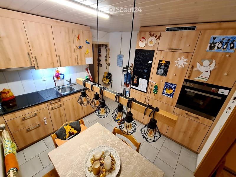 kitchen with dining area, wooden cabinets, black countertops, hanging lamps, dining table with decorative items, oven, sink, blackboard with notes