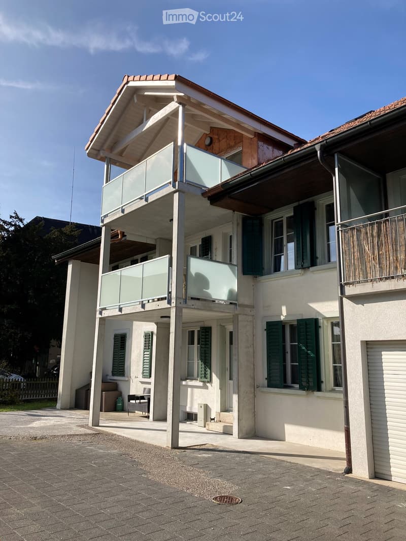 2 story house, white exterior, red roof, green shutters, 2 balconies, raised ground floor, garage