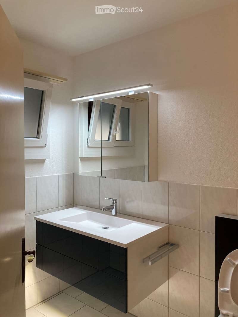 Bathroom with white sink, mirror, and tiled walls