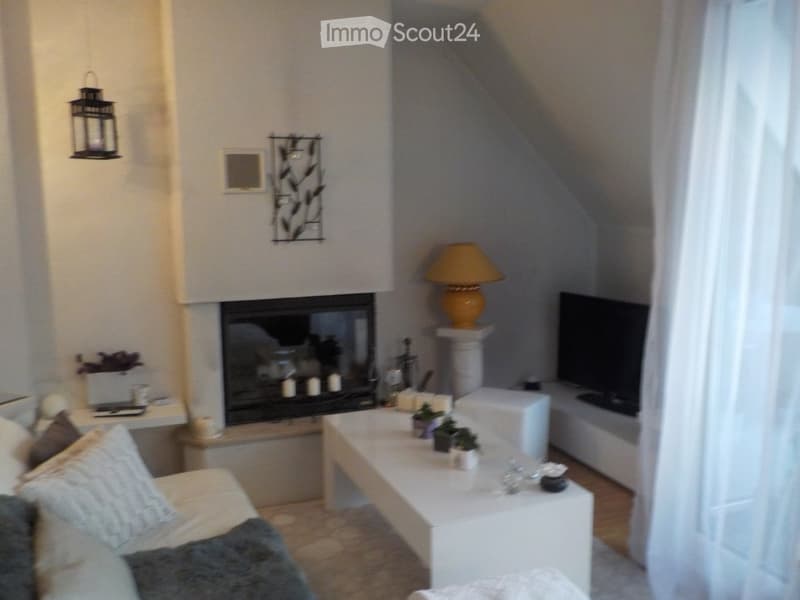 Living room with a fireplace, sofa, coffee table, table lamp, television, and decorative wall art.