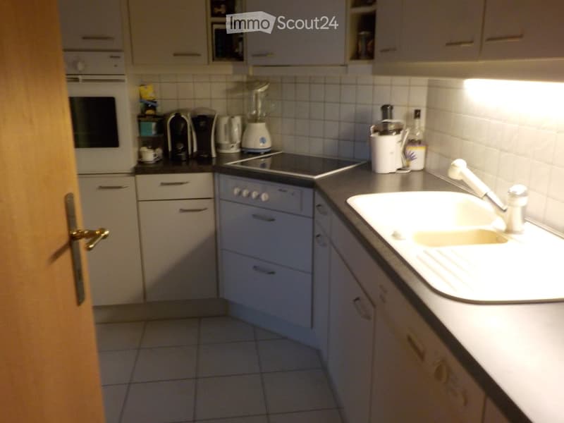 Modern kitchen with white cabinets, a sink, an oven, and various appliances including a coffee maker and a blender on the counter.