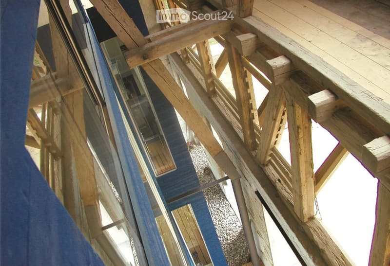 Wooden framework of a raised ground floor structure, featuring wooden beams, supports, and a gravel base.