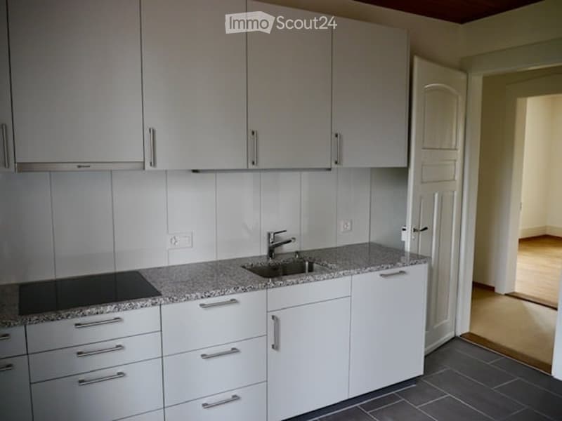Modern kitchen with white cabinets, granite countertop, stainless steel sink and faucet, and built-in stove.