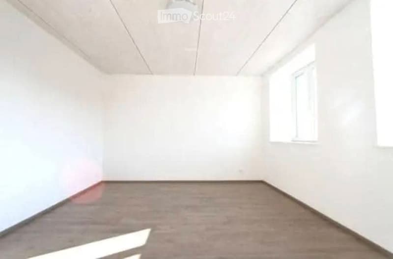 Empty room with white walls, carpeted floor, and a single window on one wall. No furniture or equipment present.