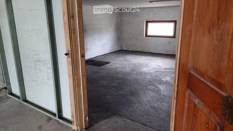 Empty room with bare concrete walls and floor, small window, and open doorway leading to another area.