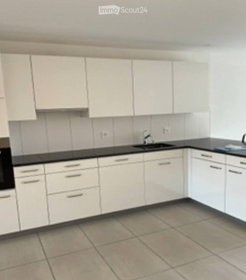 Modern kitchen with white cabinets, black countertops, and tiled flooring. Features a sink, faucet, and oven.