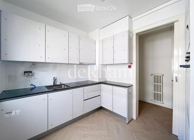 Modern kitchen with white cabinets, dark countertops, and a stainless steel sink.