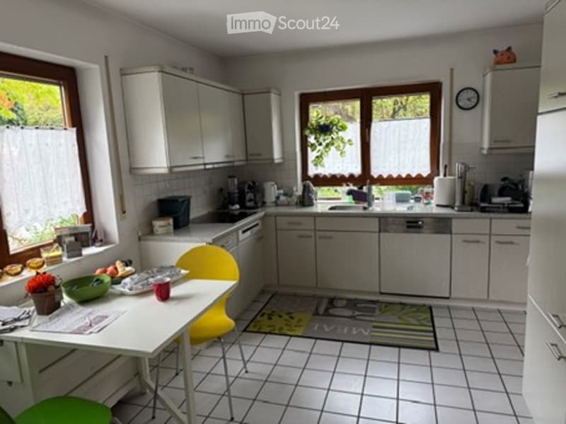 Bright kitchen with white cabinets, tiled floor, and a small dining area. Includes a table with chairs, a dishwasher, and a sink.