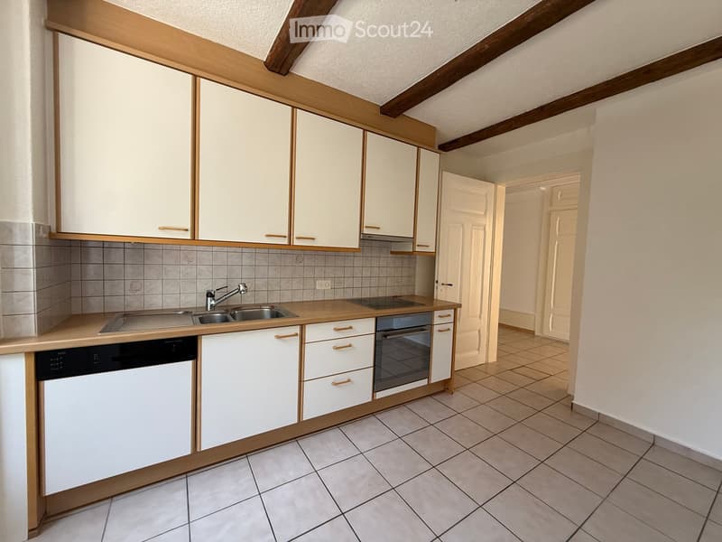 Modern kitchen with white cabinets, wooden accents, tiled backsplash, and stainless steel sink and appliances.