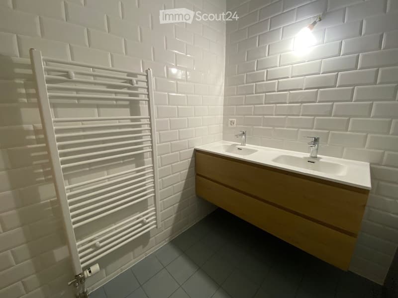 Modern bathroom with white brick walls, a double sink with wooden cabinet, and a white radiator on the left side.