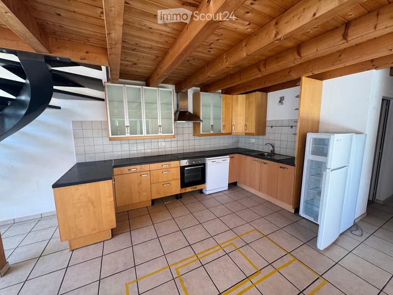 Modern kitchen with wooden cabinets, black countertops, and stainless steel appliances including a refrigerator, oven, and dishwasher.