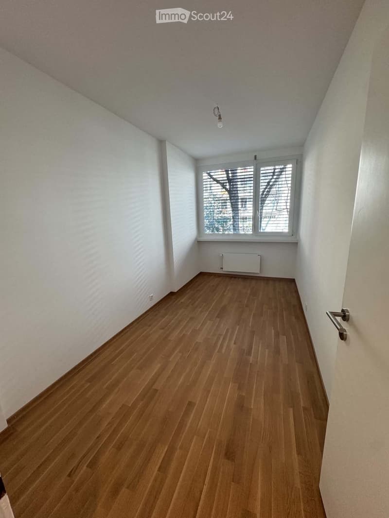 Empty room with wooden flooring, white walls, and a window with blinds. No furniture or equipment is present.