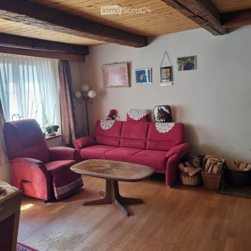 Living room with red sofa, armchair, coffee table, floor lamp, and decorative items on the wall.