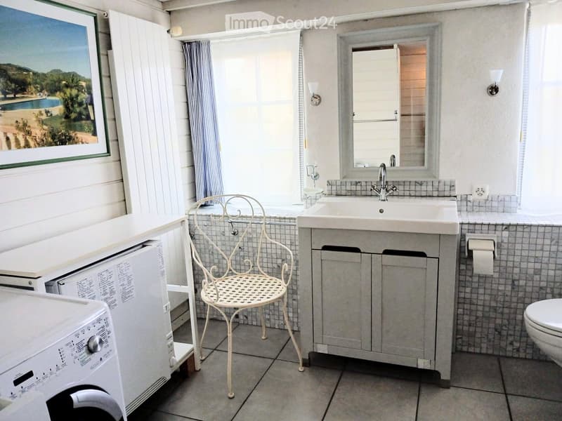 small bathroom with a sink, chair, washing machine, mirror and a toilet