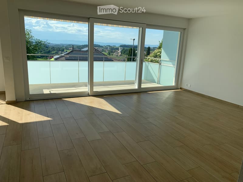 Empty room with wooden flooring and large sliding glass doors leading to a balcony with a scenic view.
