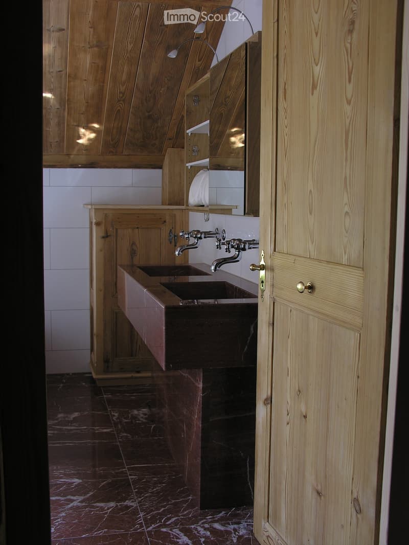 wooden ceiling, wooden cabinet, white tiled wall, wooden door, double sink, brass faucet, mirror