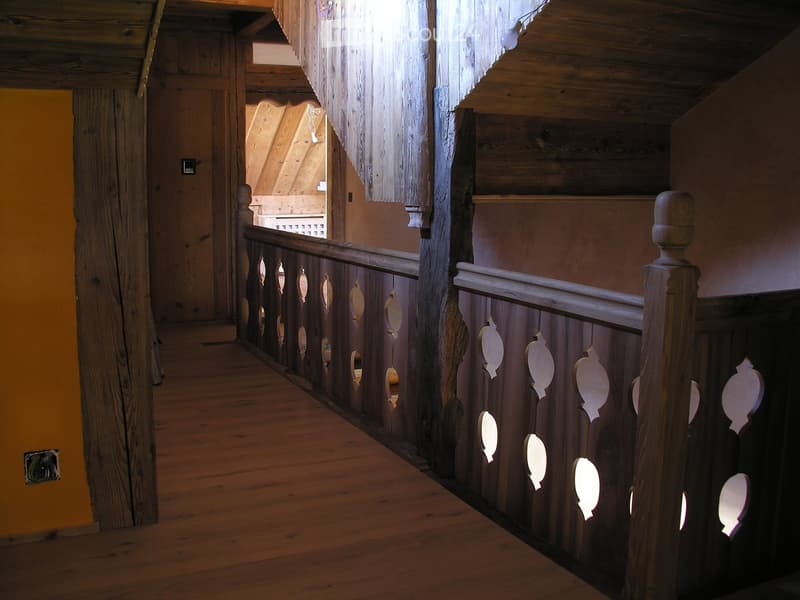 wooden railing, wooden beams on ceiling, wooden flooring, wooden pillars, yellow wall
