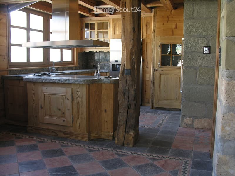 kitchen with wood cabinets, stone counter top, stainless steel appliances, chimney, window