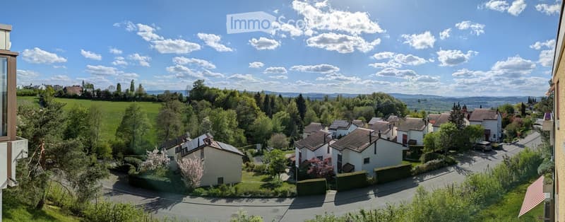 A scenic view of a residential area with houses, trees, and a clear blue sky.