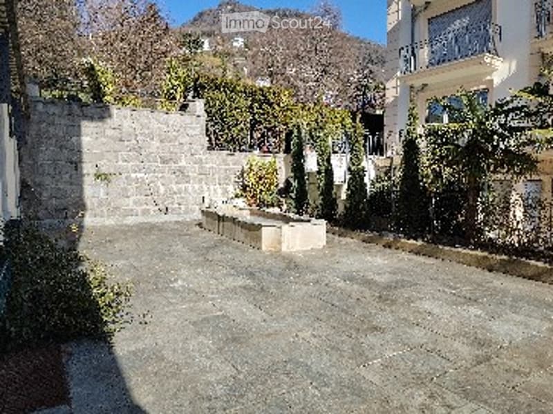Courtyard with stone walls, a small fountain, and a view of mountains in the background.