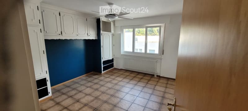Empty room with tiled floor, white cabinets, a window, and a radiator. No furniture or equipment present.