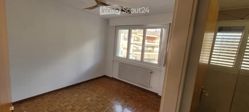 Empty room with wooden flooring, white walls, a window with blinds, a radiator, and a ceiling fan.