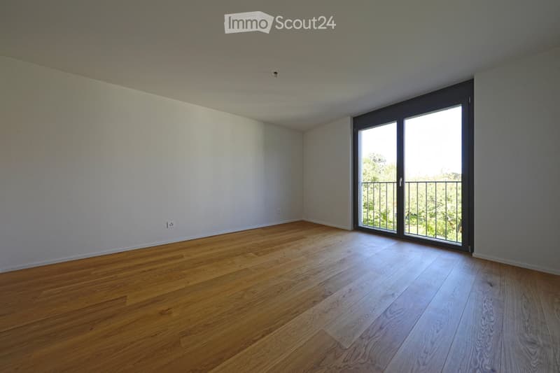 Empty room with wooden flooring, white walls, and large sliding glass doors leading to a balcony.