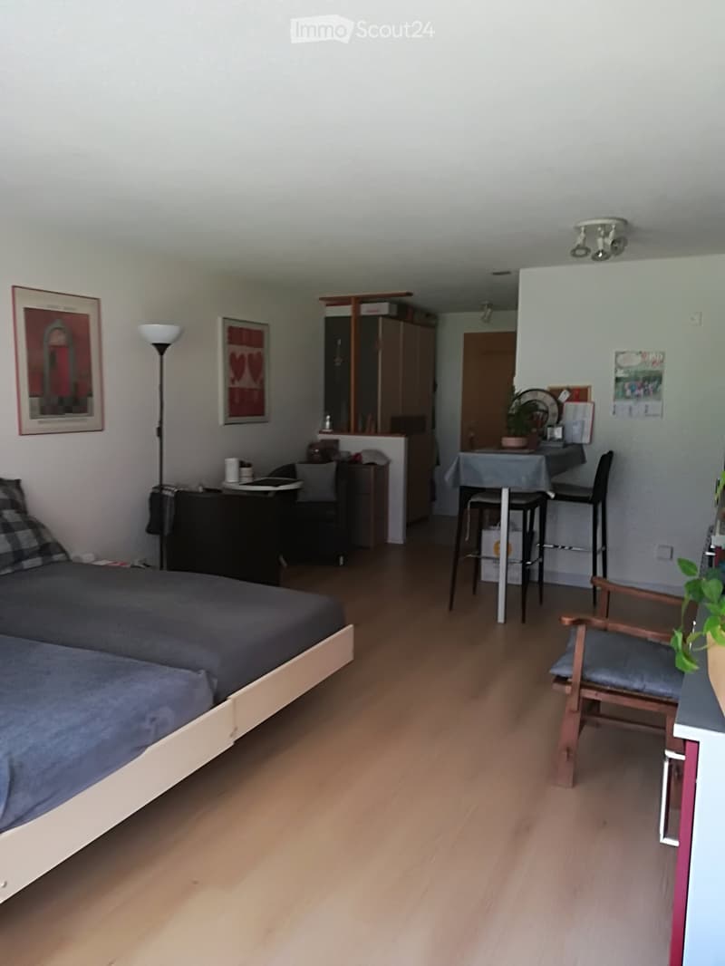 Bedroom with two beds, desk, small couch, high chair, round table, lamp