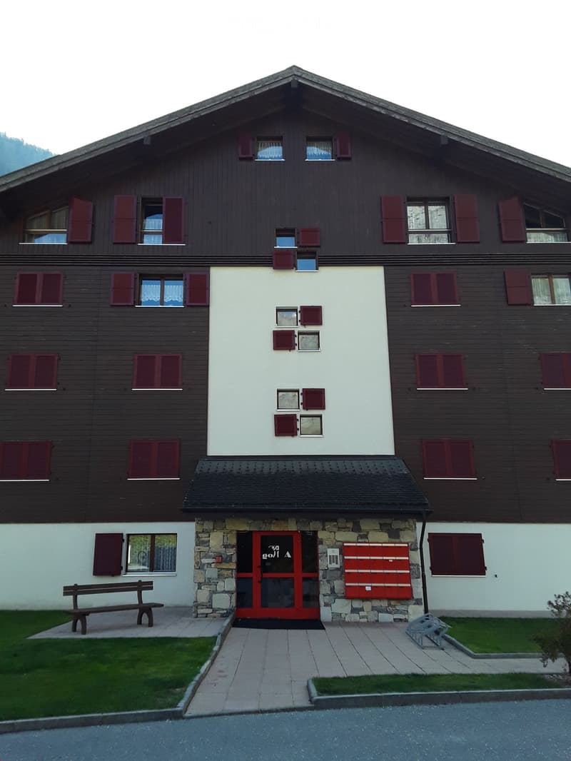 Apartment building with 3 floors, red shutters, red entrance door, red walls on entrance.