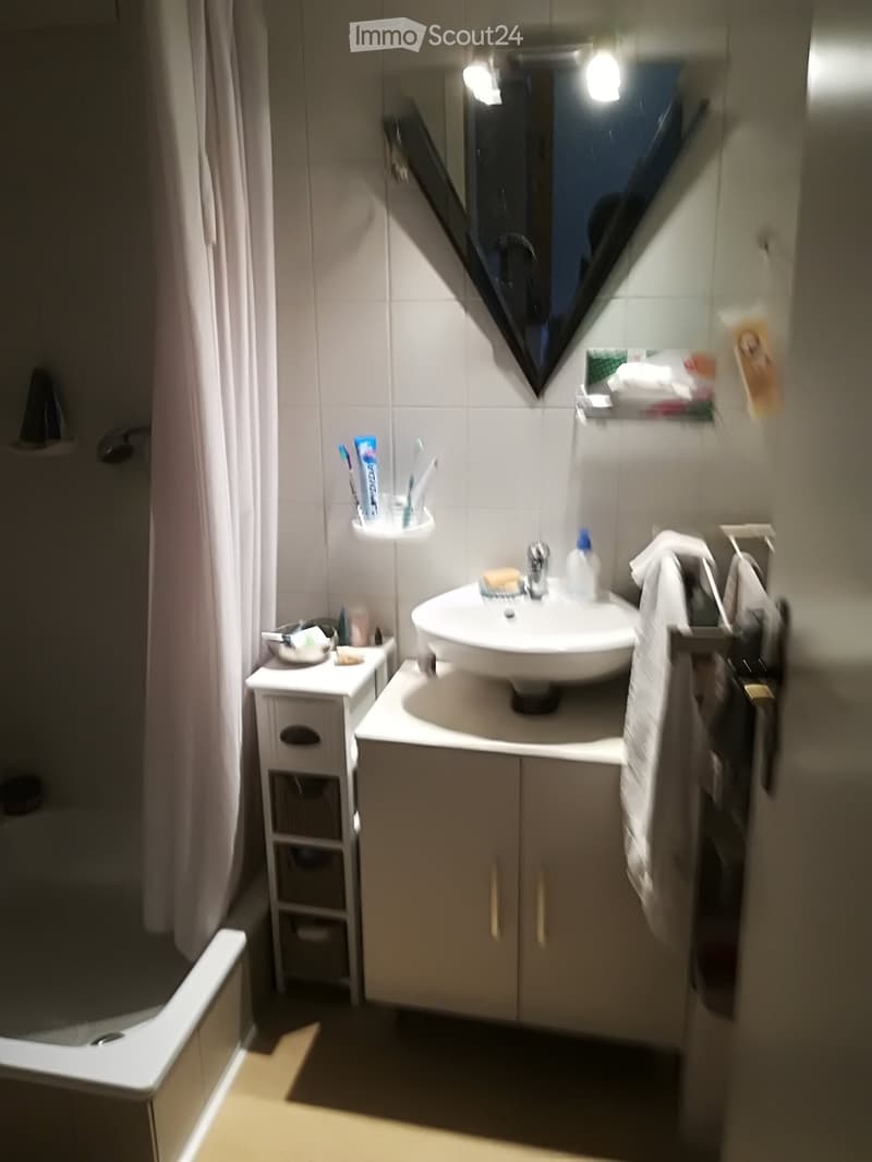 Bathroom: white tile, bathtub, shower curtain, sink, toilet paper holder, toiletries