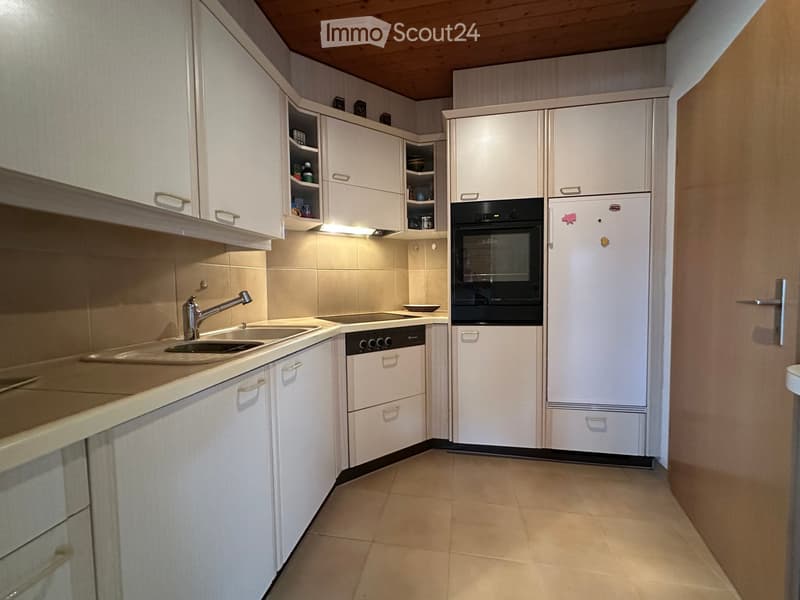 Modern kitchen with white cabinets, stainless steel appliances, and a light-colored tiled floor.
