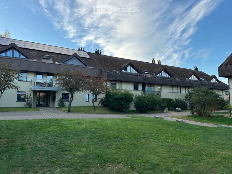 Two-story residential building with a modern design, featuring a combination of beige and brown exterior walls, multiple windows, and a well-maintained lawn in front.
