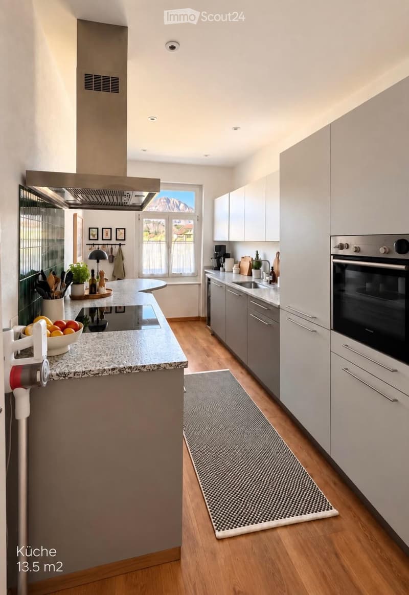 Modern kitchen with white cabinets, granite countertop, island, built-in oven, sink, and various appliances.