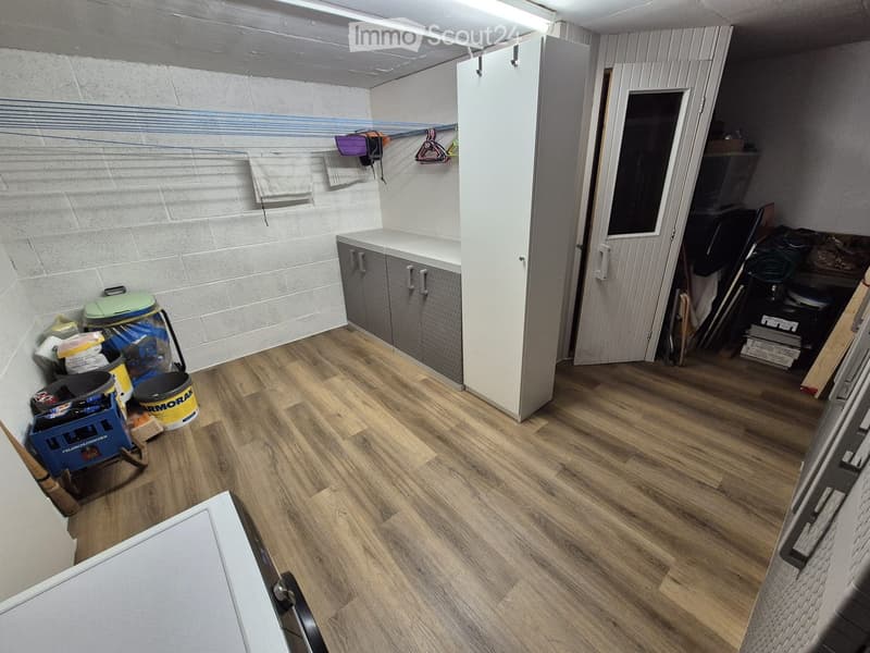Empty room with wooden flooring, white walls, and a small cabinet. Various items are stored in the corner, but no furniture is present.