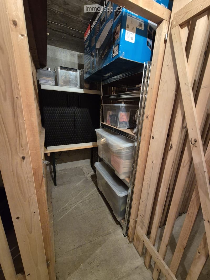 Empty storage area with wooden shelving, plastic bins, and a small table with drawers.
