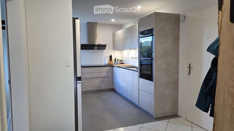 Modern kitchen with white and grey cabinets, built-in oven, countertop, and stainless steel appliances.