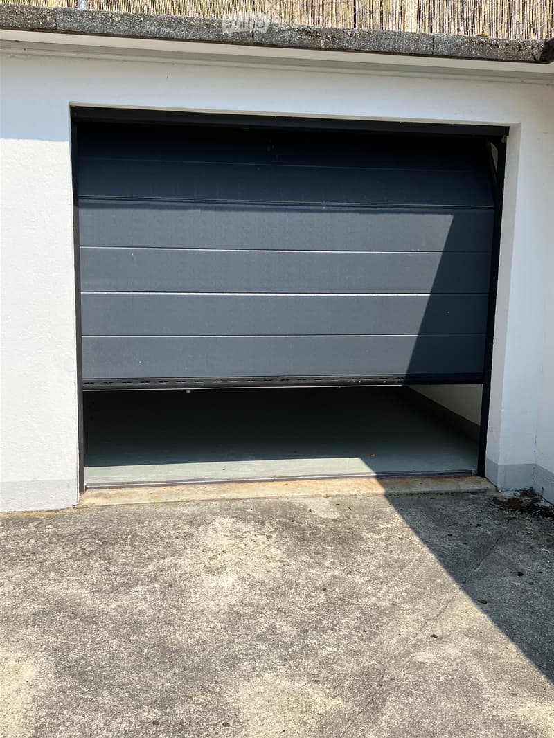 {"visible_features": ["Garage"], "type": "Garage", "description": "White garage with black sliding door, concrete floor, small window"}