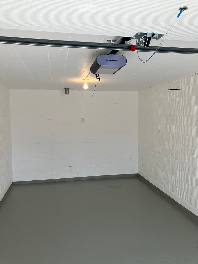 {"visible_features": ["Garage"], "type": "Garage", "description": "empty garage with ceiling mounted garage door, white brick walls, and gray concrete floor"}