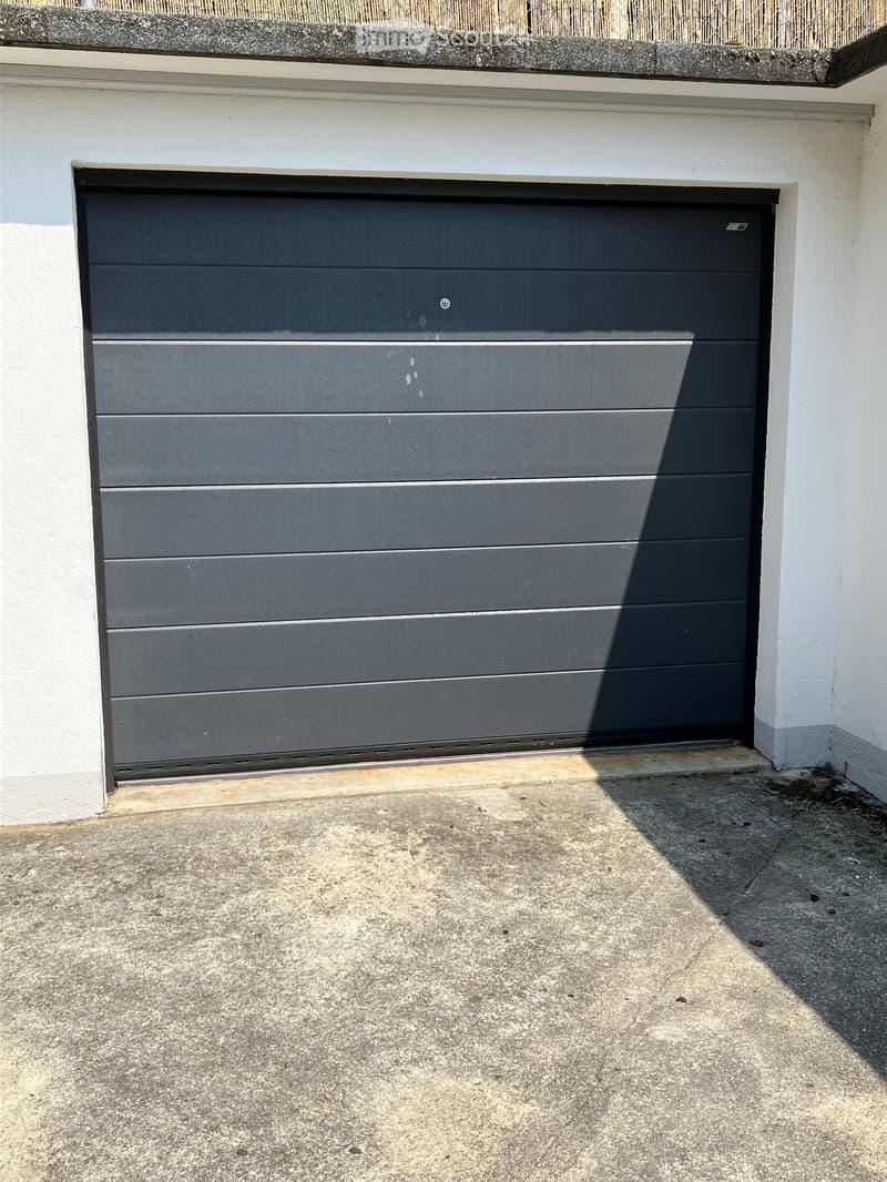 Black steel garage door, gray concrete floor, white wall